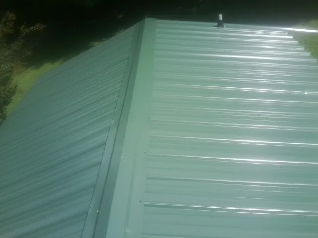 New green metal panels meeting at the ridge of a roof — Flat Roof Repair work by our crew in Zion