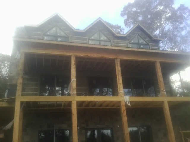 Dormers and porch framing on a large log home under construction — Roof Coating work by our crew in Zion