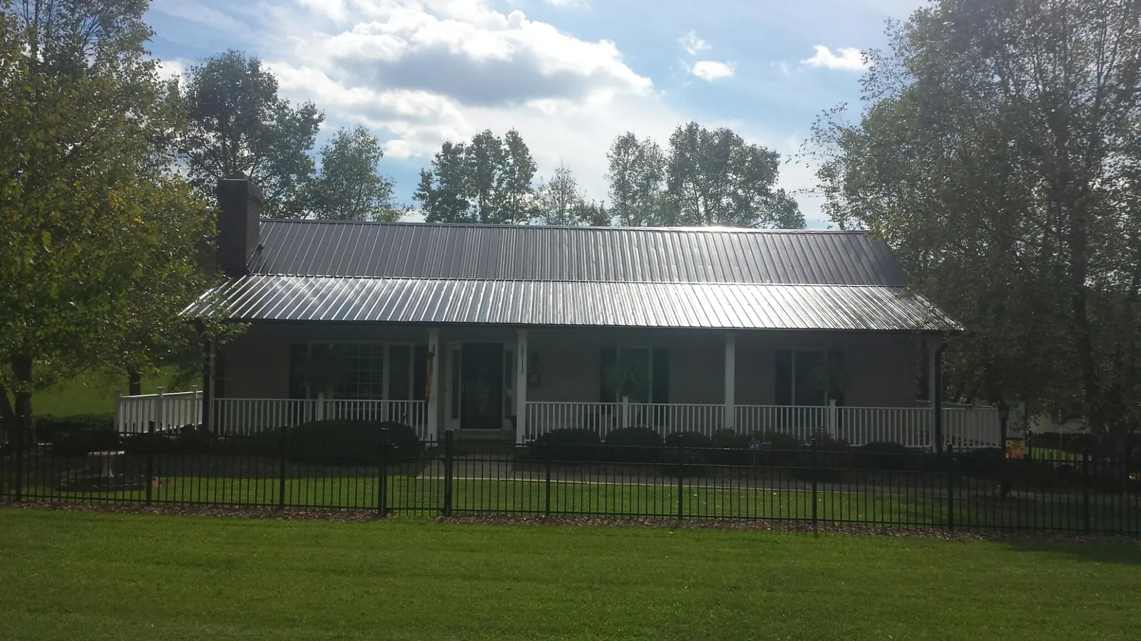 Gray metal roof on a brick ranch with a full width front porch — Gutter Guard Installation work by our crew in Zion