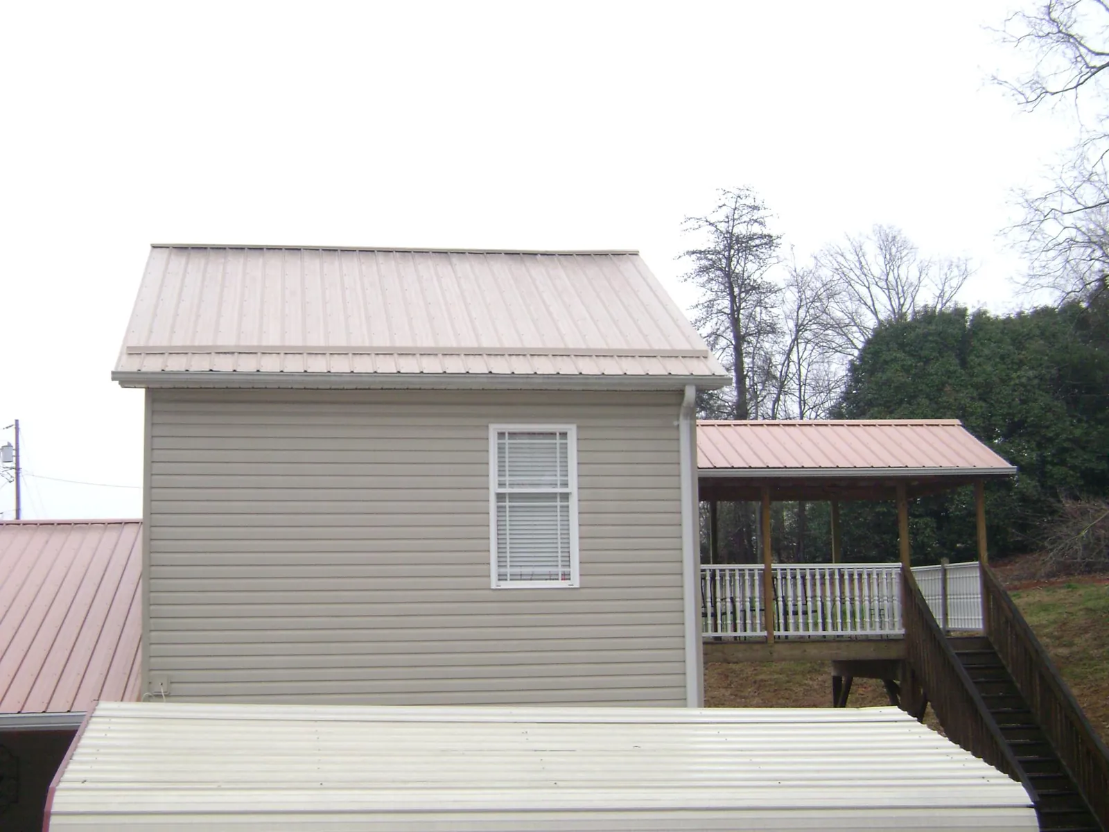 Tan metal roofs on a two story addition and attached porch, from a Roof Replacement job in Zion