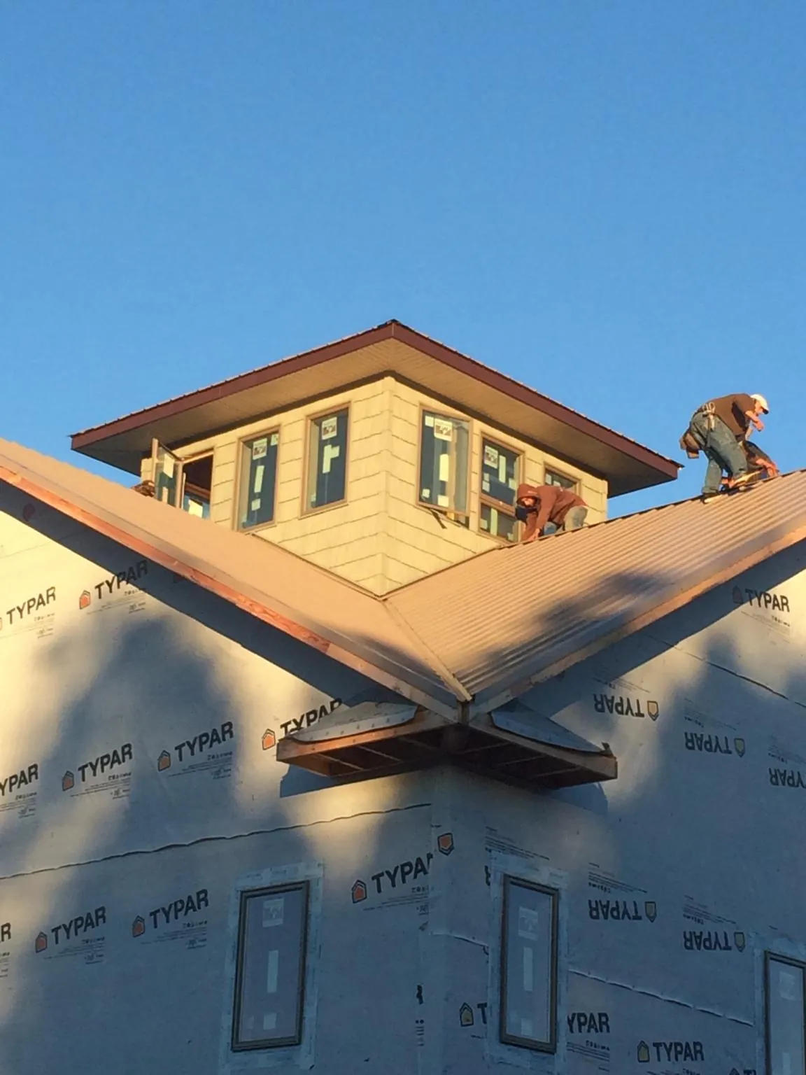 Roofers working around a rooftop cupola on a new metal roof at sunset — Roof Waterproofing in Zion by Roofing Brothers